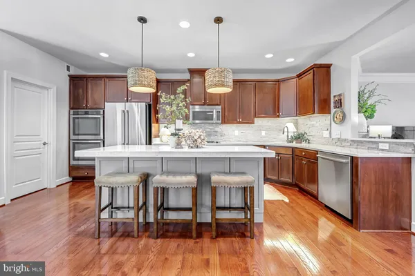 a kitchen with stainless steel appliances kitchen island granite countertop a table chairs and a refrigerator