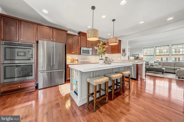a kitchen with stainless steel appliances a stove a sink a refrigerator and wooden floor