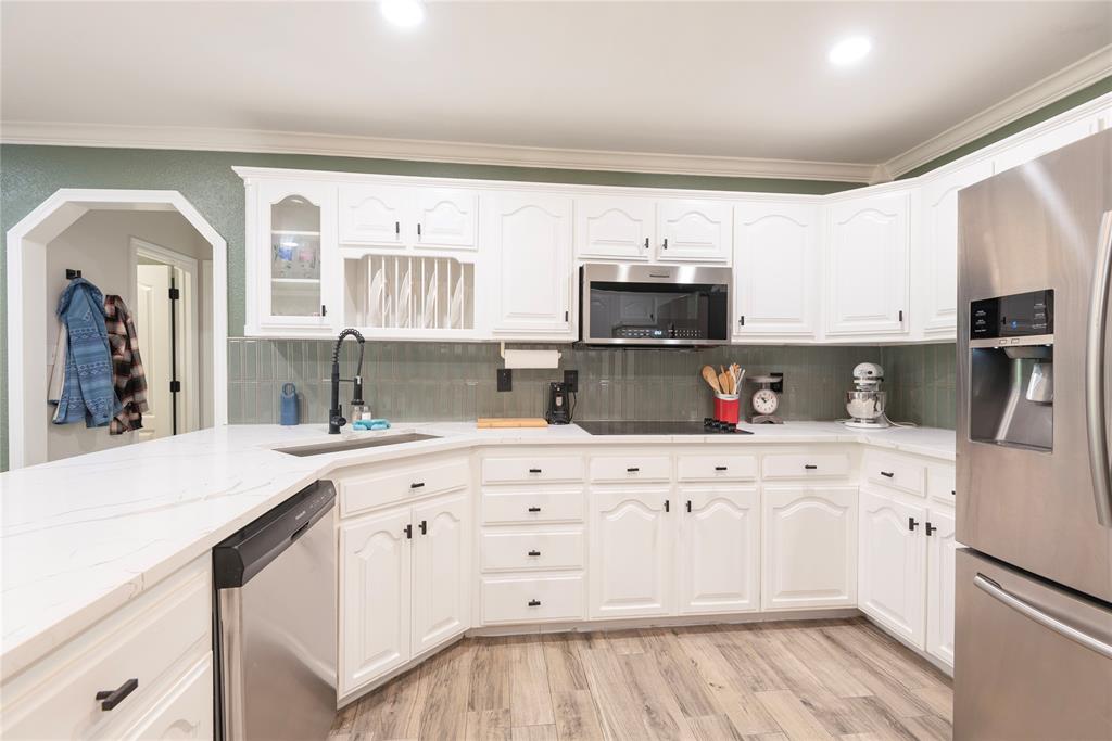 2020 Arbor Bend Road Bonham, TX 75418 - Photo 10 of 40 Kitchen with stainless steel appliances, light wood-style floors, white cabinets, crown molding, and light stone counters