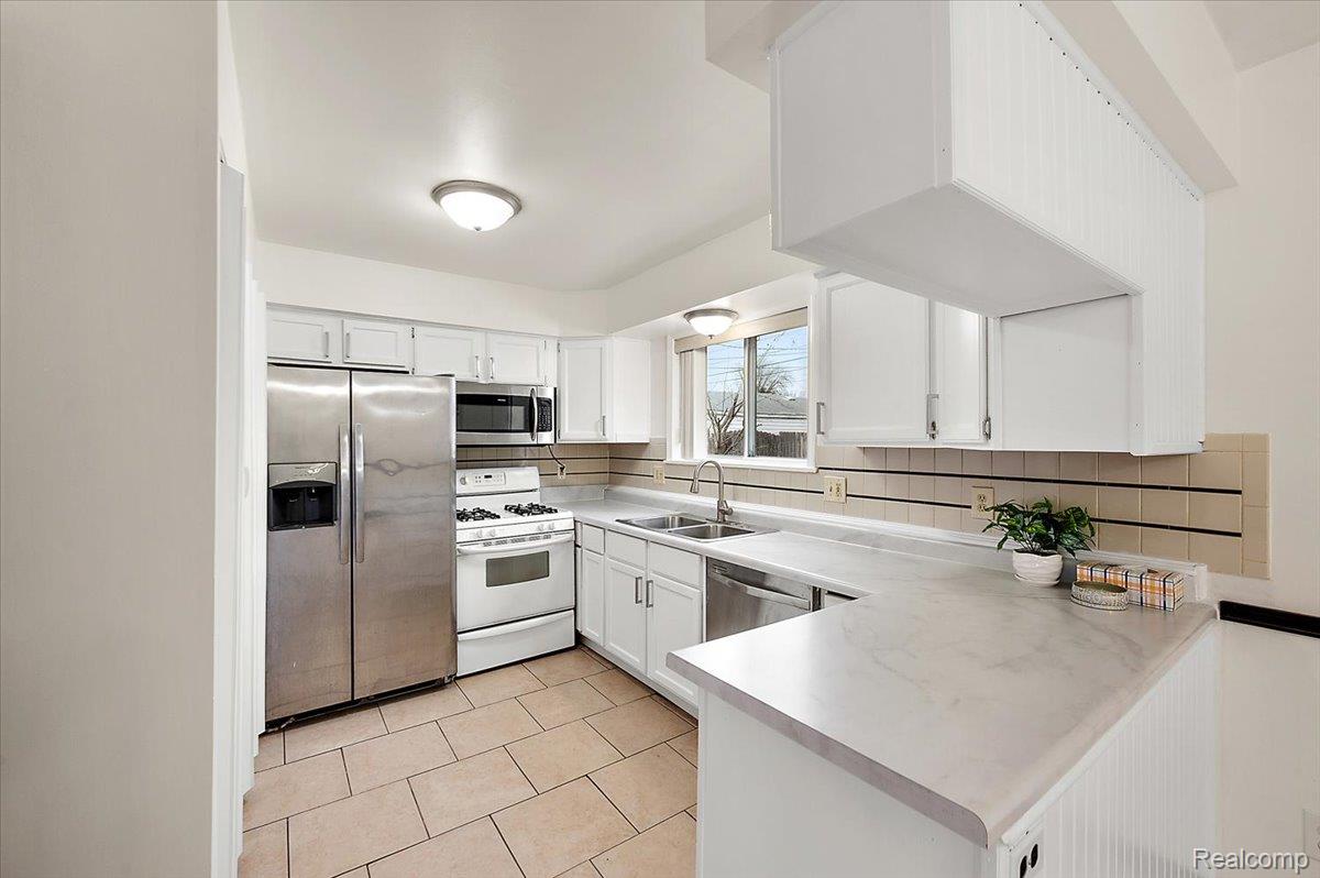 32416 Exeter Drive Warren, MI 48092 - Photo 11 of 33 Kitchen with appliances with stainless steel finishes, light countertops, white cabinetry, light tile patterned floors, and a peninsula