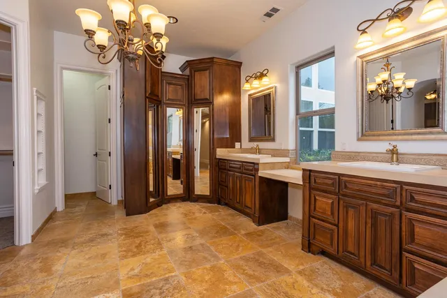 a spacious bathroom with a granite countertop double vanity sink a mirror a vanity and a bathtub