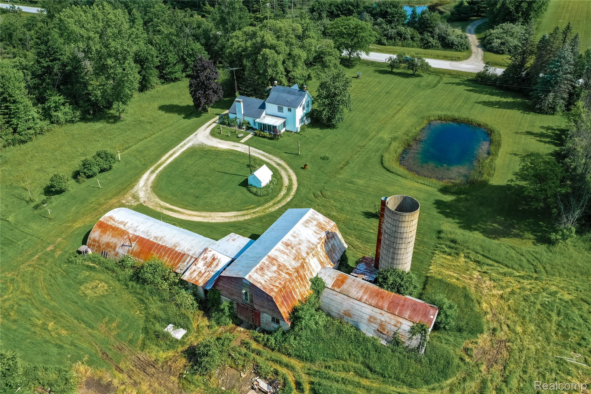 8384 Imlay City Road Avoca, MI 48006 - Photo 1 of 39 Expansive property featuring a primary residence, multiple outbuildings including a barn structure and silo, and a pond