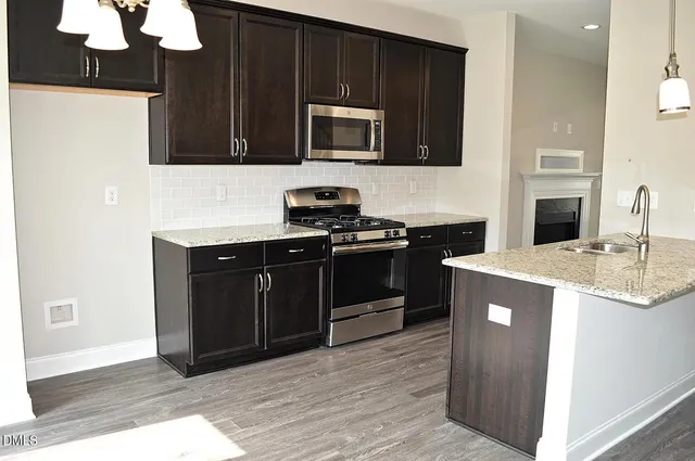 a kitchen with stainless steel appliances granite countertop a sink a microwave refrigerator and a cabinets