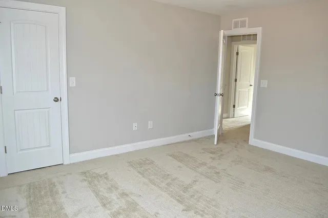 a view of an empty room with wooden floor and a kitchen