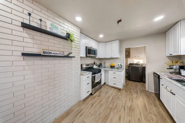 a kitchen with cabinets wooden floor and stainless steel appliances