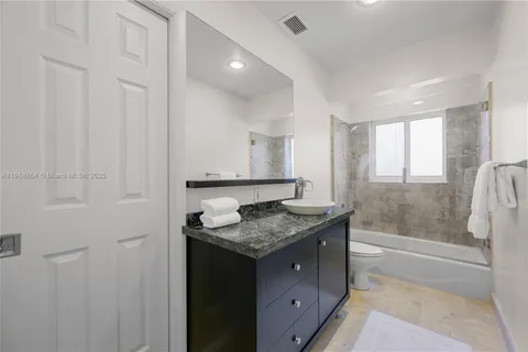 a bathroom with a granite countertop sink and a bathtub