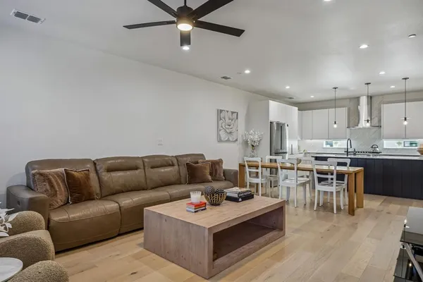 a living room with furniture kitchen view and a chandelier