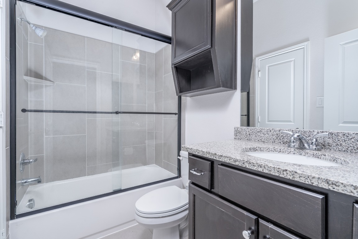 1232 Lakeside Ranch Road Georgetown, TX 78633 - Photo 27 of 31 a bathroom with a granite countertop sink toilet and shower