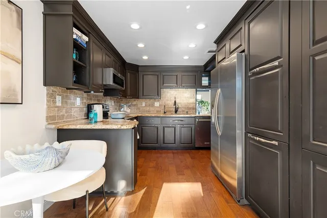 a kitchen with stainless steel appliances granite countertop a sink a stove a refrigerator and a microwave