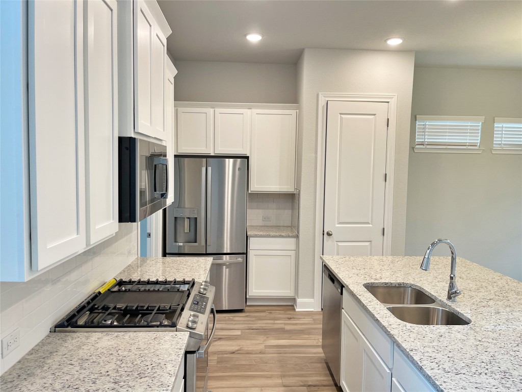 143 Delaware Lane Kyle, TX 78640 - Photo 5 of 30 a kitchen with kitchen island granite countertop a refrigerator and a sink