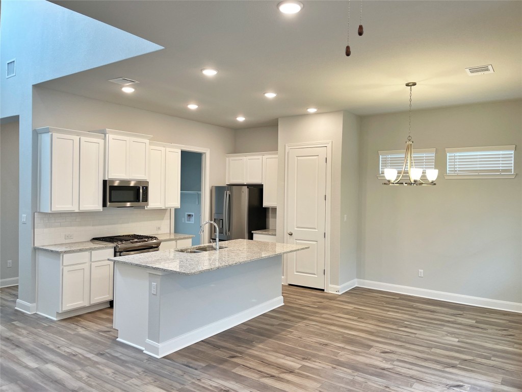 143 Delaware Lane Kyle, TX 78640 - Photo 7 of 30 a large kitchen with stainless steel appliances kitchen island a large counter top and wooden floor
