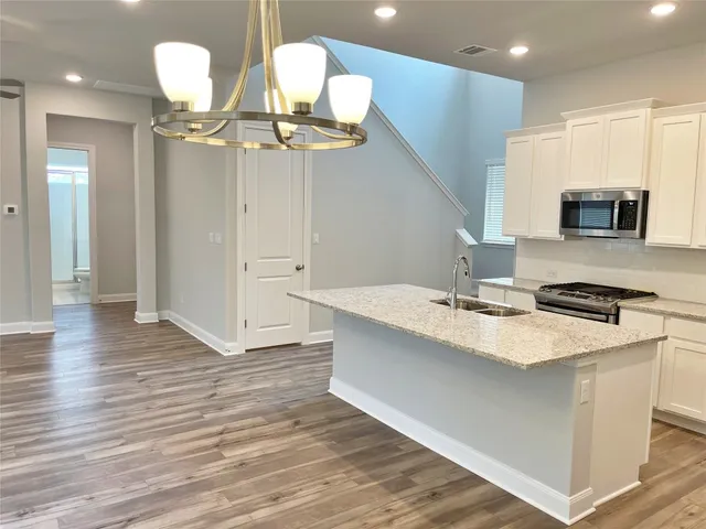 a kitchen with a sink a chandelier and wooden floor