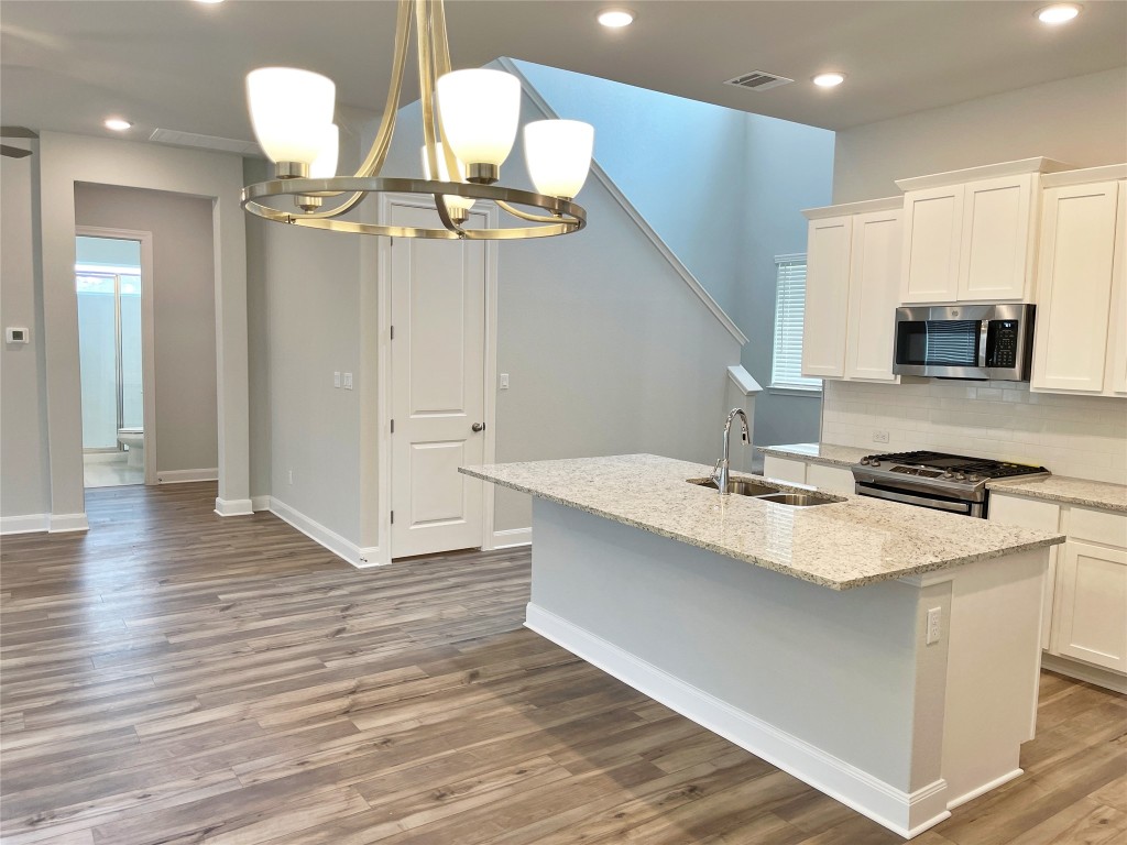 143 Delaware Lane Kyle, TX 78640 - Photo 8 of 30 a kitchen with a sink a chandelier and wooden floor