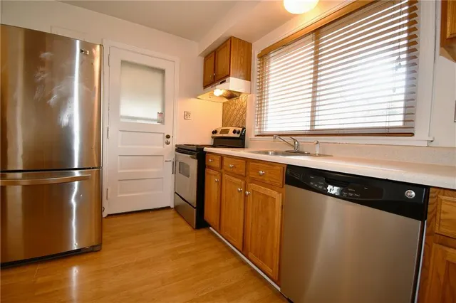 a kitchen with stainless steel appliances a refrigerator a sink and cabinets