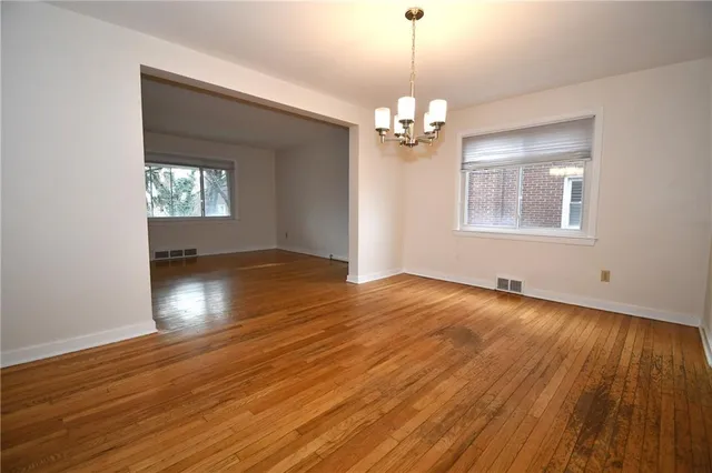 a view of empty room with wooden floor and chandelier