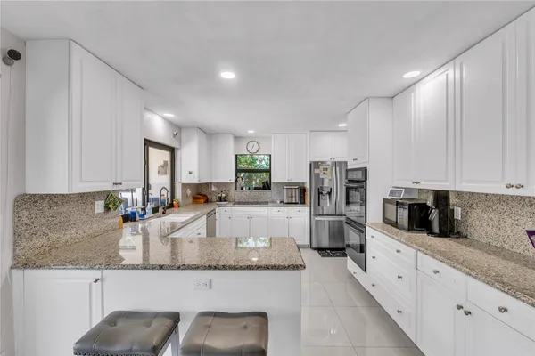 a large kitchen with granite countertop a large counter top stainless steel appliances and cabinets