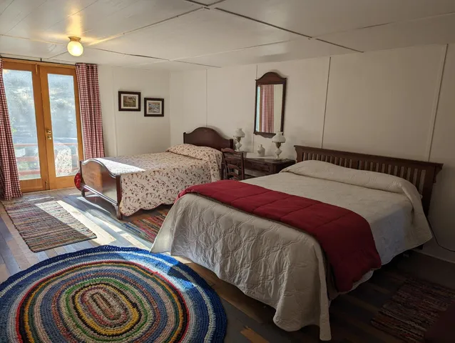 a bedroom with two beds and wooden floor
