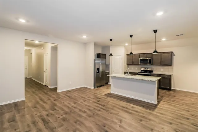 a kitchen with stainless steel appliances kitchen island granite countertop a refrigerator and a sink