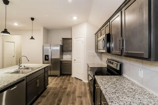 a kitchen with stainless steel appliances granite countertop a sink stove and refrigerator