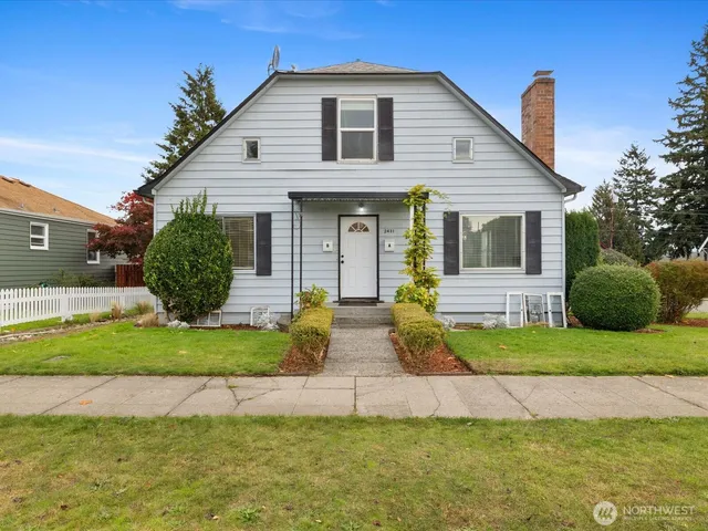 a view of a white house next to a yard and large trees