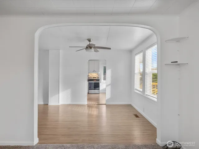 a view of an empty room with wooden floor and a window