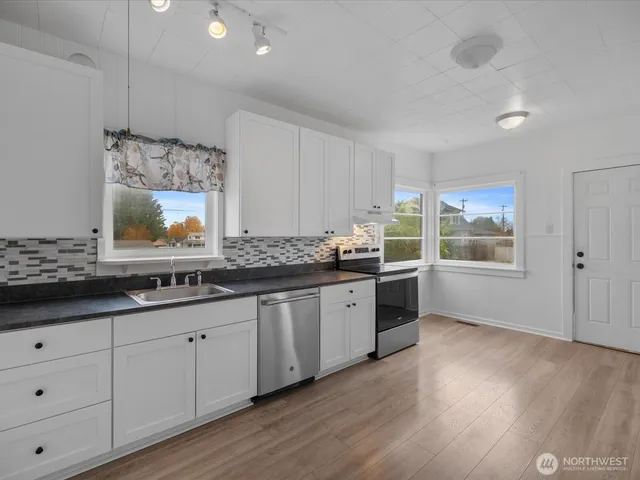 a large kitchen with granite countertop a large window and white cabinets