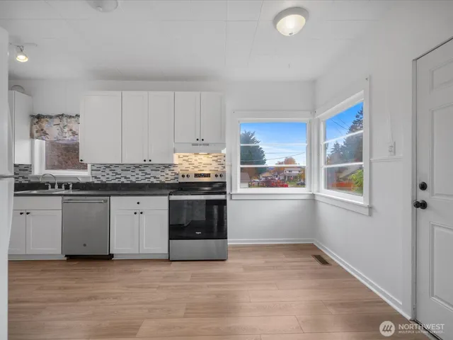 a kitchen with stainless steel appliances granite countertop a stove a sink and a refrigerator
