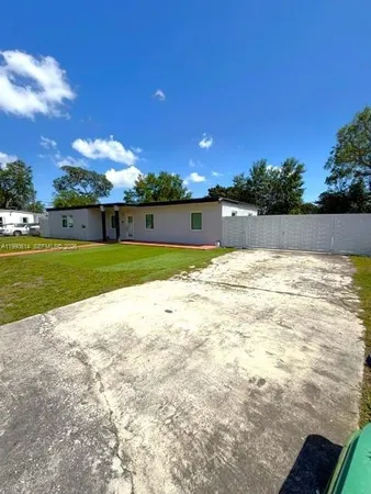 a view of a large pool with lawn chairs under an umbrella