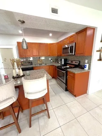 a view of kitchen with stainless steel appliances kitchen island granite countertop a sink and cabinets