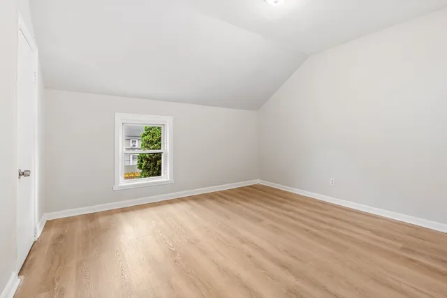 an empty room with wooden floor and window