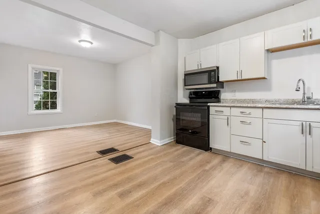 a kitchen with granite countertop white cabinets and stainless steel appliances