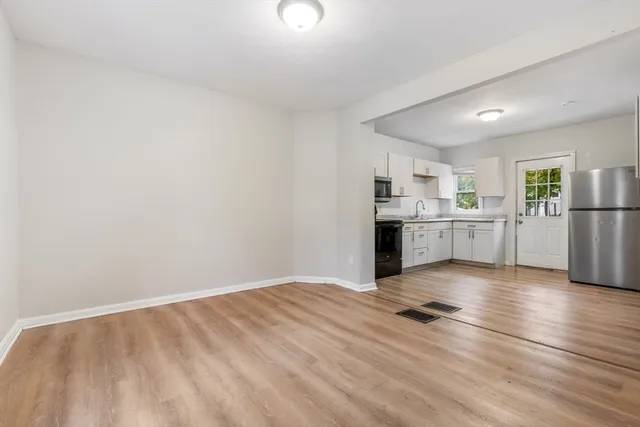 a view of a kitchen with wooden floor electronic appliances and cabinets