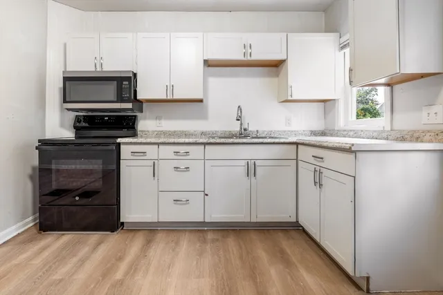 a kitchen with granite countertop white cabinets and stainless steel appliances