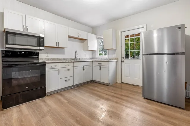 a kitchen with white cabinets stainless steel appliances and a window
