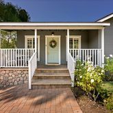 a view of a house with potted plants and a bench