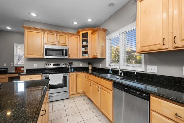 a kitchen with stainless steel appliances granite countertop dining table chairs cabinets and a window
