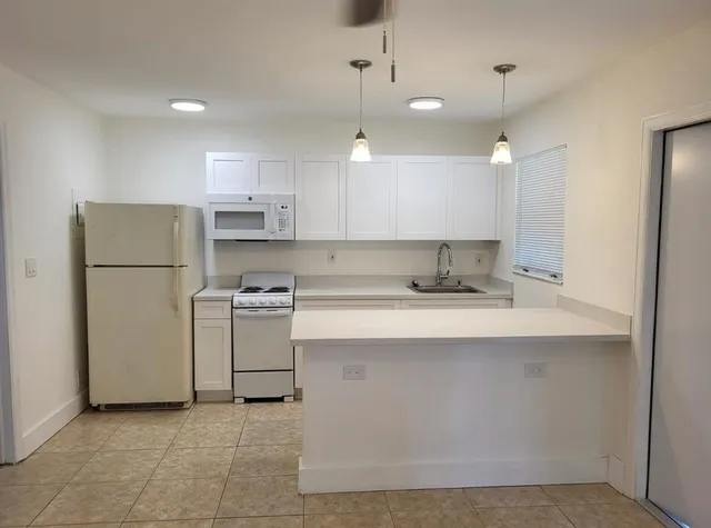 a kitchen with a sink a refrigerator and white cabinets