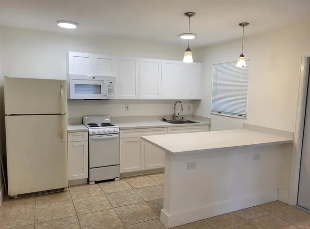 a kitchen with a sink a refrigerator and cabinets