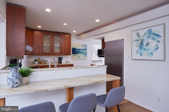 a kitchen with stainless steel appliances granite countertop wooden cabinets a stove top oven a sink and dishwasher a dining table with garden view