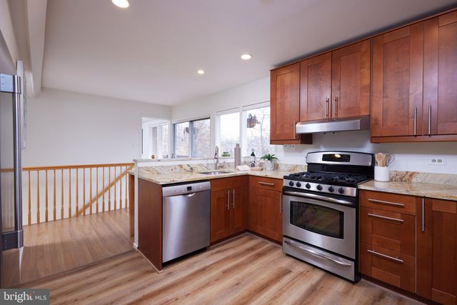 a room with stainless steel appliances granite countertop a refrigerator a stove and a sink