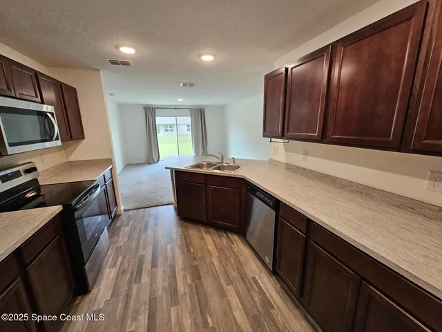 a kitchen with a sink wooden floor and stainless steel appliances