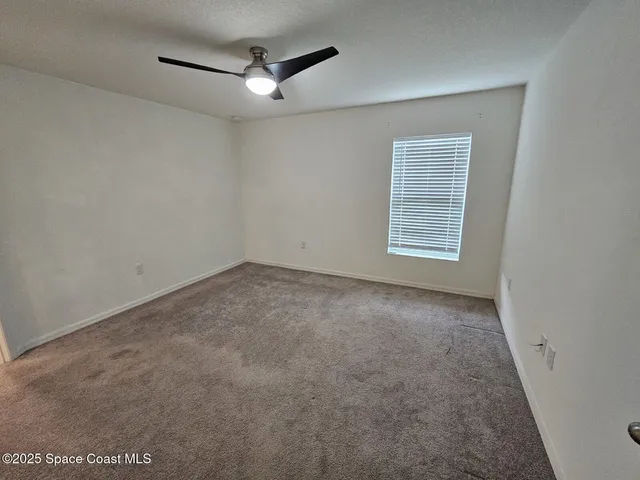 an empty room with a ceiling fan and window