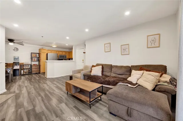a living room with furniture and kitchen view with wooden floor