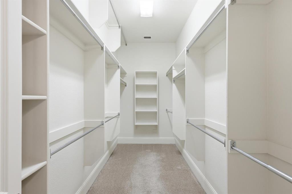 516 Sandy Lane Flower Mound, TX 75022 - Photo 20 of 38 Expansive walk-in closet featuring extensive built-in shelving, multiple hanging rods, recessed lighting, and soft carpeting