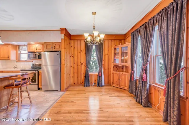 a kitchen with stainless steel appliances a dining table chairs refrigerator and sink