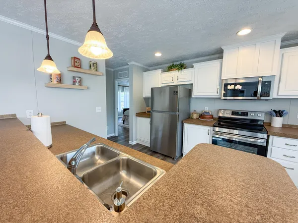 a kitchen with stainless steel appliances granite countertop a sink a stove and a refrigerator