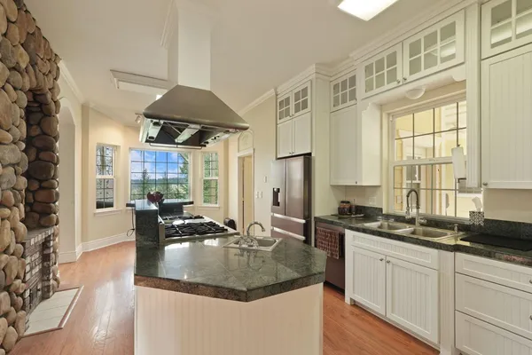 a kitchen with a stove a sink and wooden floor