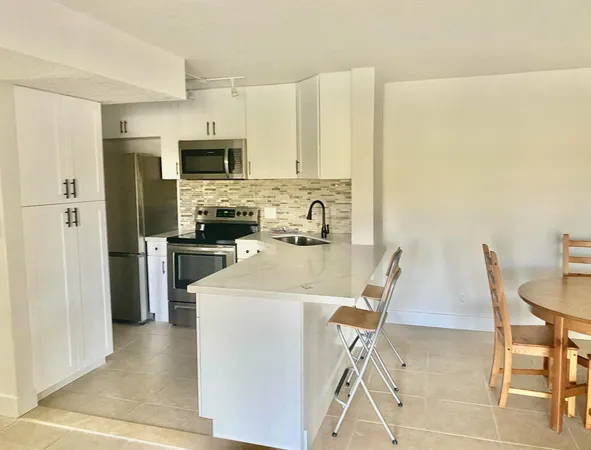 a kitchen with stainless steel appliances a stove a refrigerator a sink a dining table and chairs