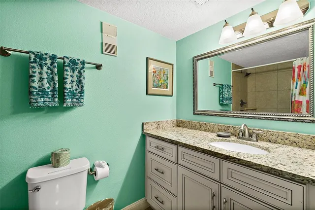 a bathroom with a granite countertop sink a mirror and a toilet