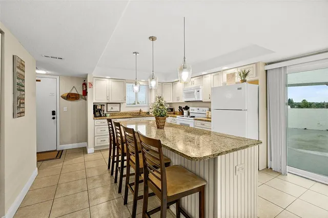 a kitchen with stainless steel appliances a refrigerator a stove a kitchen island with a dining table and chairs